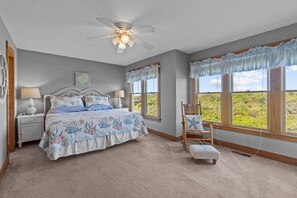 A bedroom with a bed, two nightstands, a chair, a window with curtains, and a ceiling fan. - 2410 - Come Sail Away - Steps to the Sand | Oceanfront Duck Retreat (Duck)