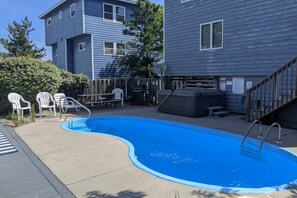 A residential swimming pool with a wooden deck, white plastic chairs, and a metal ladder. - 1886 - Got Beach - Corolla Semi-Oceanfront | Pool & Hot Tub (Corolla)