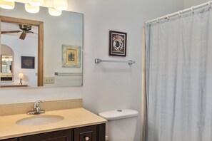 A bathroom with a sink, mirror, toilet, and shower curtain. - 1886 - Got Beach - Corolla Semi-Oceanfront | Pool & Hot Tub (Corolla)