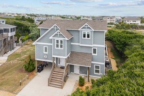 A two-story house with a front porch, a staircase leading to the entrance, and a small front yard.