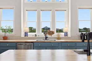 A kitchen with a large window, a sink, and a potted plant.