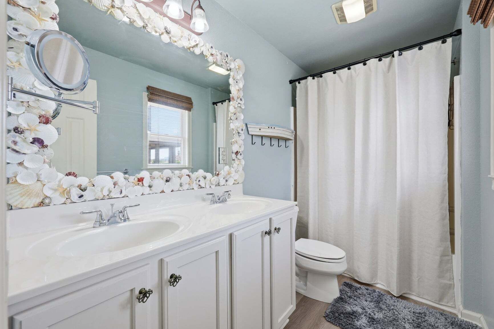 A bathroom with a white vanity, a large mirror, a toilet, and a shower curtain.