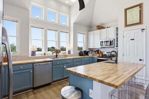 Een keuken met een houten aanrecht, blauwe kastjes, een vaatwasser en een magnetron.