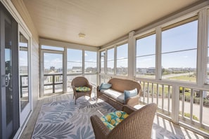 A covered porch with wicker furniture, large windows, and a view of the city.