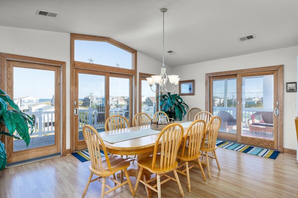 A dining area with a wooden table and chairs, large windows, and a view of the city.