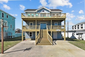 A two-story building with a balcony, a staircase, and a basketball hoop.