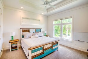 Ein Schlafzimmer mit einem Bett, zwei Nachttischen, einem Deckenventilator, einem Fenster und einer Whiteboard-Tafel.