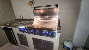A stainless steel outdoor kitchen with a grill, a sink, and a propane tank. - NO Bunks-King beds, Garage Parking, Private Beach Access-Less Crowded (Siesta Key)