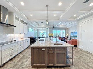 A spacious kitchen with a large island, modern cabinetry, and a view to the living area.