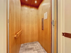 A narrow elevator with wooden walls and a metal control panel.