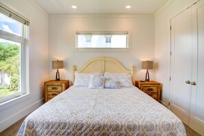 A bedroom with a bed, two bedside tables with lamps, a window, and a door.