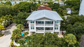 A multi-story house with a balcony, surrounded by lush greenery and a view of a lake. - NO Bunks-King beds, Garage Parking, Private Beach Access-Less Crowded (Siesta Key)