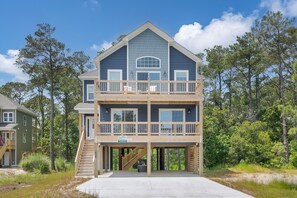 Relax on the spacious deck with a staircase leading to an upper level, surrounded by lush greenery and trees.