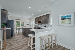 A modern kitchen with a central island, bar stools, and a dining area with a view.