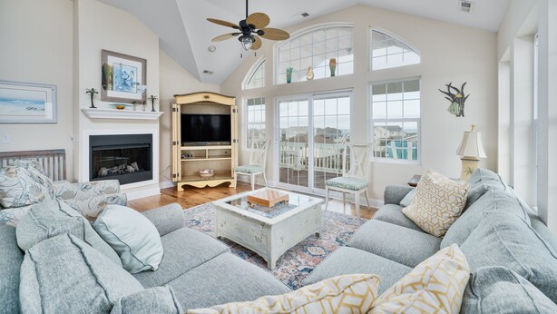A spacious living room with a large gray sofa, a fireplace, and a ceiling fan. - 4763- Smells Like Sea Spirit, Kitty Hawk Beach House | Pool & Game Room (Kitty Hawk)