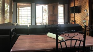 A cozy room with a wooden ceiling, a sofa, a dining table with chairs, and a TV mounted on the wall. - Villa by the Sea (Playa Grande)