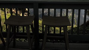 A wooden deck with two benches overlooking a calm river, surrounded by lush greenery and a bridge in the background. - Newly remodeled Riverfront 3 bedroom house on the Great Chazy River with dockage (Champlain)