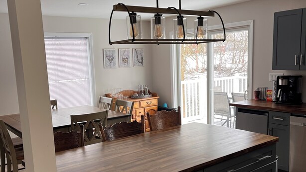 A modern kitchen with a central island, grey cabinetry, and a pendant light fixture. - Newly remodeled Riverfront 3 bedroom house on the Great Chazy River with dockage (Champlain)