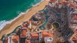 An aerial view of a coastal resort with a beachfront, swimming pools, and a central courtyard. - Ocean front over looking the arch in Cabo San Lucas, with golf access (Cabo San Lucas)