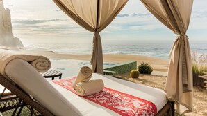 A beachside room with a bed, a small table, and a view of the ocean. - Ocean front over looking the arch in Cabo San Lucas, with golf access (Cabo San Lucas)