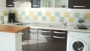 A modern kitchen with a washing machine, a coffee maker, and a dish rack. - Beautiful apartment for 4 people (BISCARROSSE)