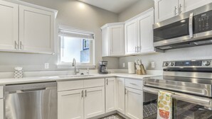 Une cuisine moderne avec des meubles blancs, des appareils en acier inoxydable et un tapis à motifs.
