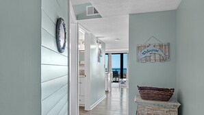 A hallway with light blue walls, wooden flooring, and a welcome sign.