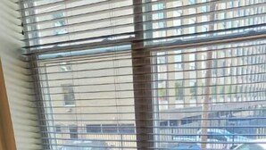 A dining table with two chairs, a window with blinds, and a view of the street outside. - FAB Studio Near Capitol, Hospitals, & Fair Grounds (Jackson)
