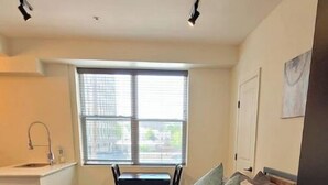 A bedroom with a bed, pillows, a window, a sink, and a chair. - FAB Studio Near Capitol, Hospitals, & Fair Grounds (Jackson)