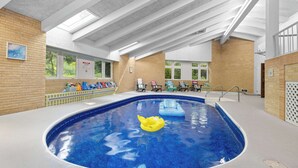 An indoor swimming pool with a clear ceiling, a yellow inflatable duck, and a seating area with chairs and a table. - Rockford Retro Revival • Indoor Pool + Arcade Fun! (Rockford)