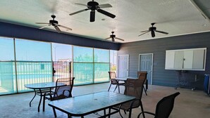 A spacious balcony with a table and chairs, large windows, ceiling fans, and a door. - Hotel O Bien Venido Pearsall I-35 (Pearsall)