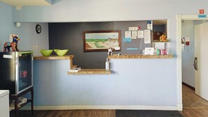 A reception desk with a framed painting, a clock, and various notices on the wall. - Hotel O Bien Venido Pearsall I-35 (Pearsall)