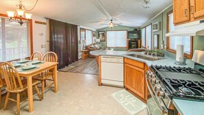 A kitchen with a dining area, wooden cabinets, a stove, and a ceiling fan. - Meadowview Clean & Comfortable Home by River Side (Klamath)