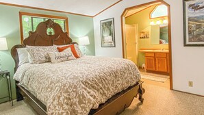 A bedroom with a large bed, a wooden headboard, a nightstand, a lamp, and a framed picture on the wall. - Meadowview Clean & Comfortable Home by River Side (Klamath)