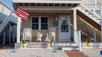 A two-story house with a front porch, a welcome sign, and an American flag.