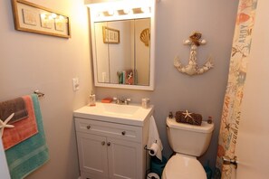 Une salle de bain équipée d’un lavabo, d’un miroir, de toilettes et d’objets décoratifs.