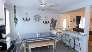 A dining area with a table, chairs, and a bar counter with stools. - Newly remodeled 3 BR, 2 Bath shore house sleeps 10. (Wildwood Crest)