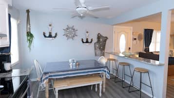 A dining area with a table, chairs, and a bar counter with stools.