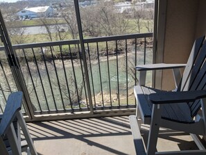 Enjoy the serene river view from this balcony, featuring a comfortable seating area with two Adirondack chairs.
