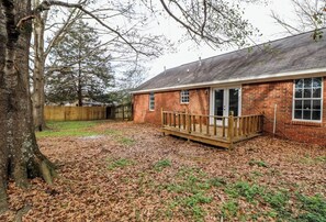 A brick building with a wooden deck and a large tree in the foreground.