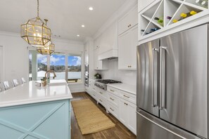 A modern kitchen with a large island, stainless steel appliances, and a view to the outside.