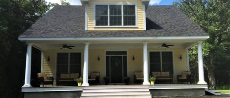 A two-story house with a porch, a front door, and two windows on the upper floor.