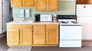 A kitchen with wooden cabinets, a white stove, a microwave, and a coffee maker.