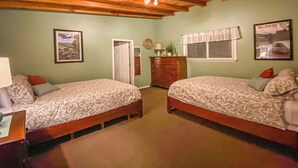 A room with two beds, a dresser, a lamp, and a framed picture on the wall.