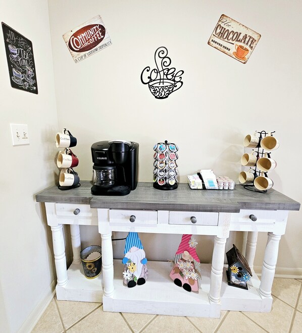 A coffee station with a Keurig coffee maker, a coffee mug rack, and a coffee bean display.