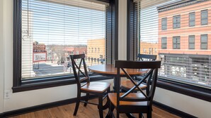 A room with two large windows, a round table, and four chairs.