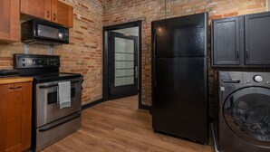 A kitchen with a brick wall, stainless steel appliances, and wooden cabinets.