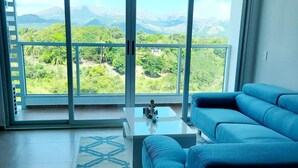 A modern living room with a large sliding glass door leading to a balcony with a mountain view. - Lovely condo with beach, mountain and pool view. (Nueva Gorgona)