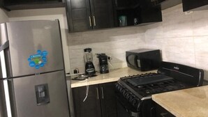 Une cuisine équipée d’un réfrigérateur en acier inoxydable, d’une machine à café, d’un four à micro-ondes et d’une cuisinière.