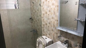 Une salle de bain avec douche, toilettes et lavabo.